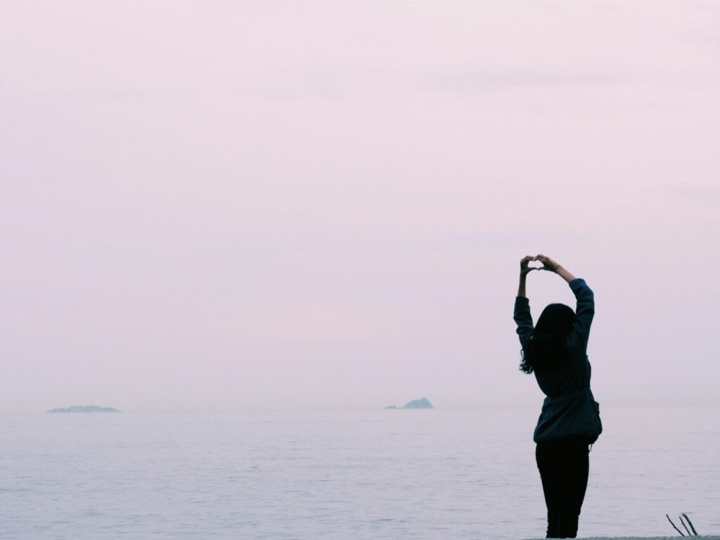 A woman at sunrise expressing her new ability of self-love